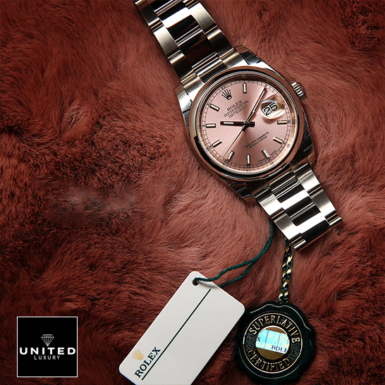 Rolex Datejust 116200-0079 Oyster Perpetual Replica 2 Rolex Datejust 116200 Pink Dial Replica next to the quarantine card on soft ground